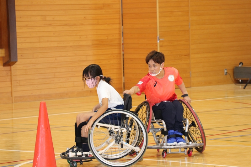 車いすに乗る児童を手伝う平井選手の写真