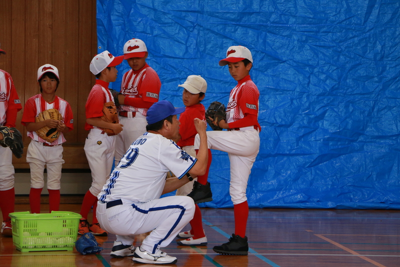 ピッチングの指導をする久保さんと子どもたちの写真