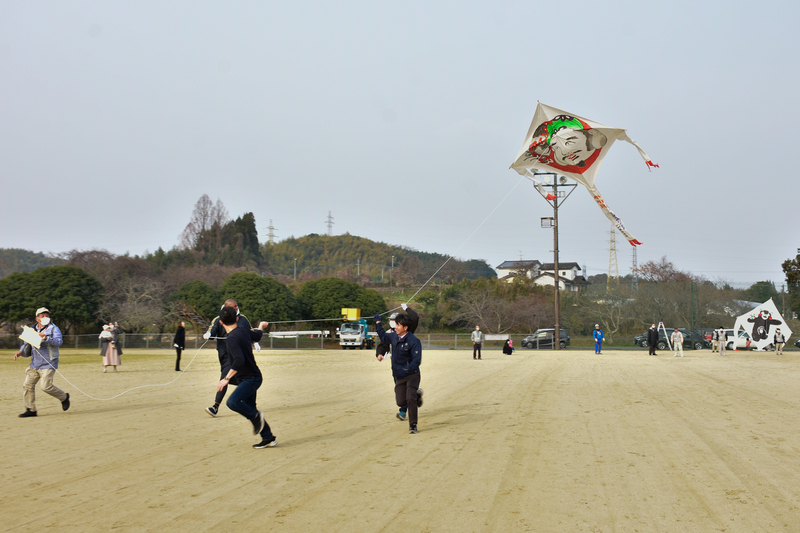 数人で大きな凧を揚げている写真