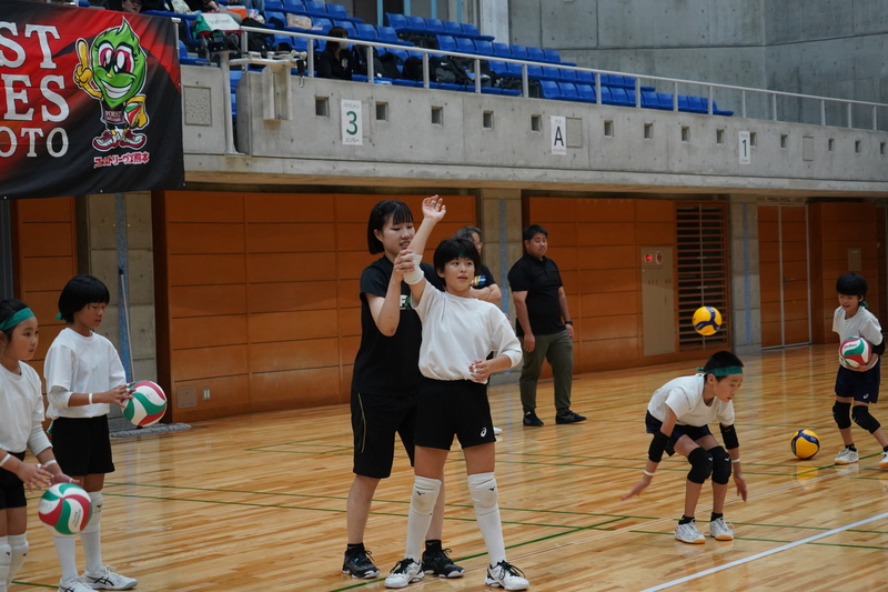 ボールを打つポイントを選手から教わるよう様子