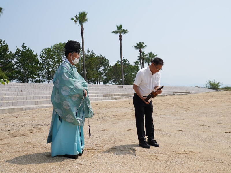 お神酒を海にそそぐ市長の写真