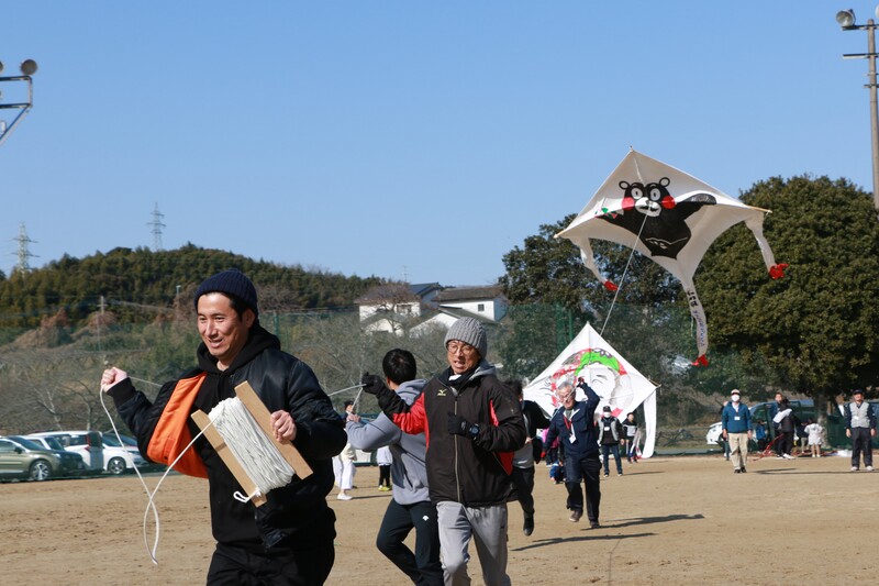 たこをあげる大人たちの写真