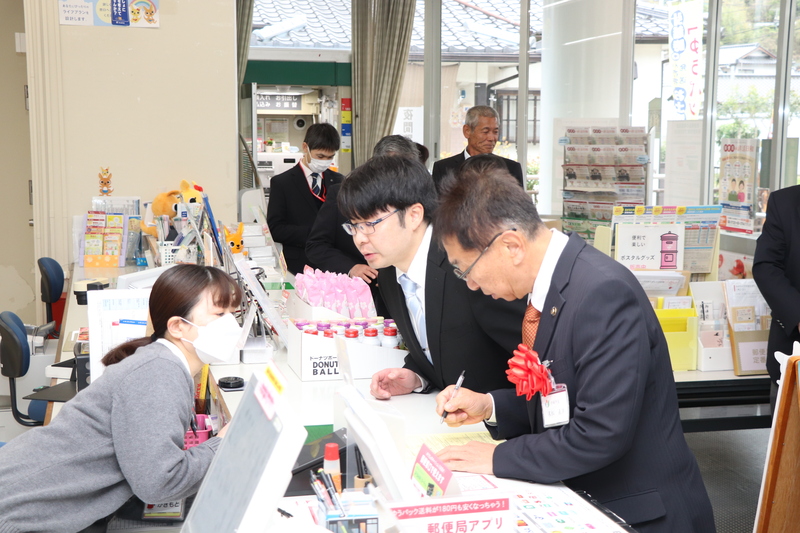松合郵便局窓口で住民票交付の手続き体験を行う末松市長の写真