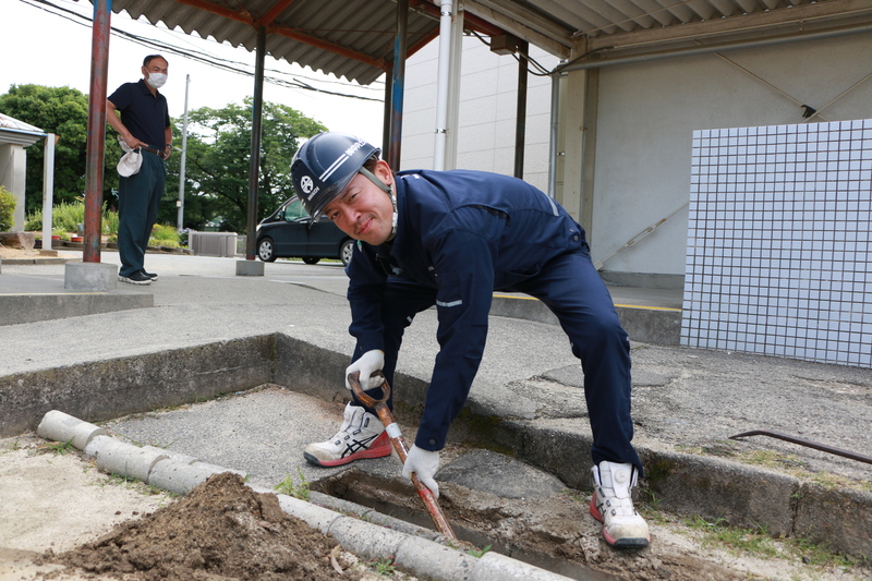 泥がたまった側溝の清掃作業中のボランティアの方の写真