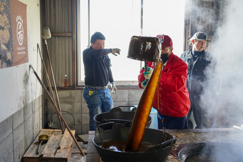 煮詰められた黒砂糖を鍋へ引き上げる様子