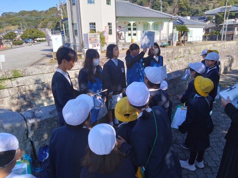 資料を見えやすいよう上に掲げながら説明する様子