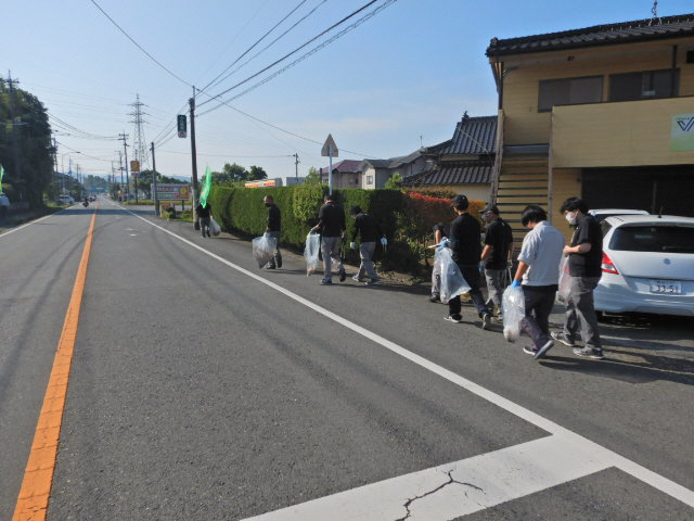 美化運動で道路を歩きながら、ごみを拾っている写真