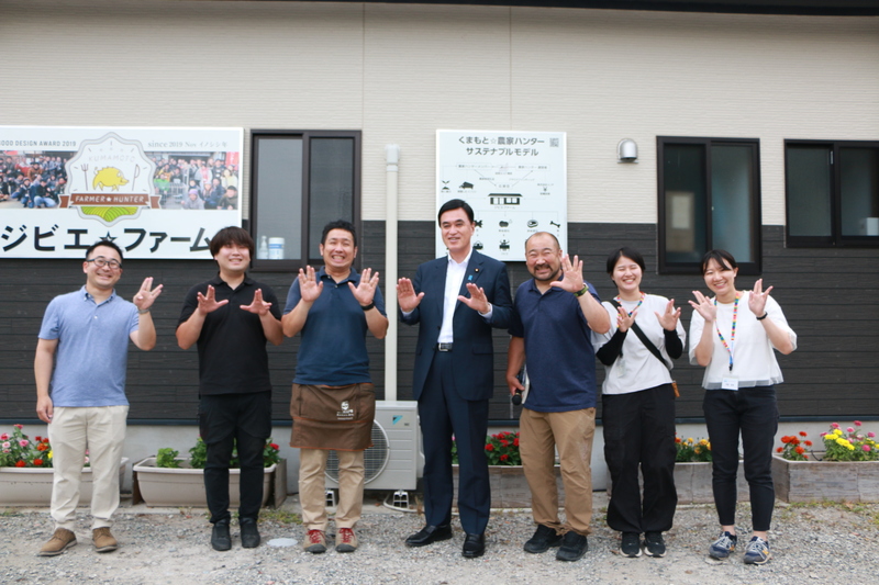 ジビエファームの前でイノシシピースで小里泰弘内閣総理大臣補佐官とイノPのメンバーでの写真