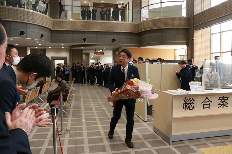 送られた花束を持ち市役所を後にする様子