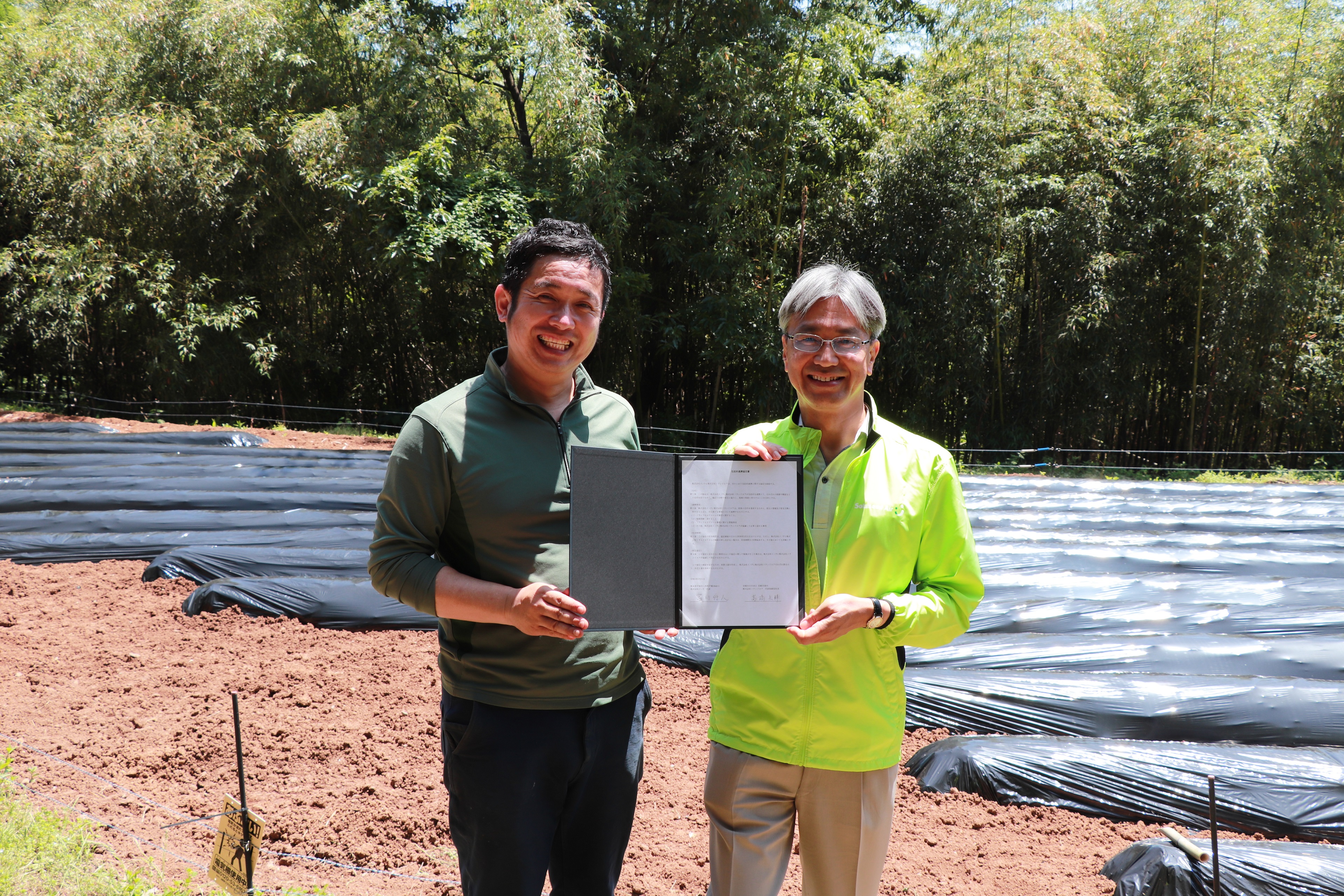 調印式を終え、包括的連携協定書を披露する宮川代表と髙橋取締役社長の写真