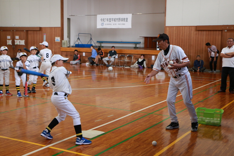 バッティングの指導をする庄司さんと子どもたちの写真