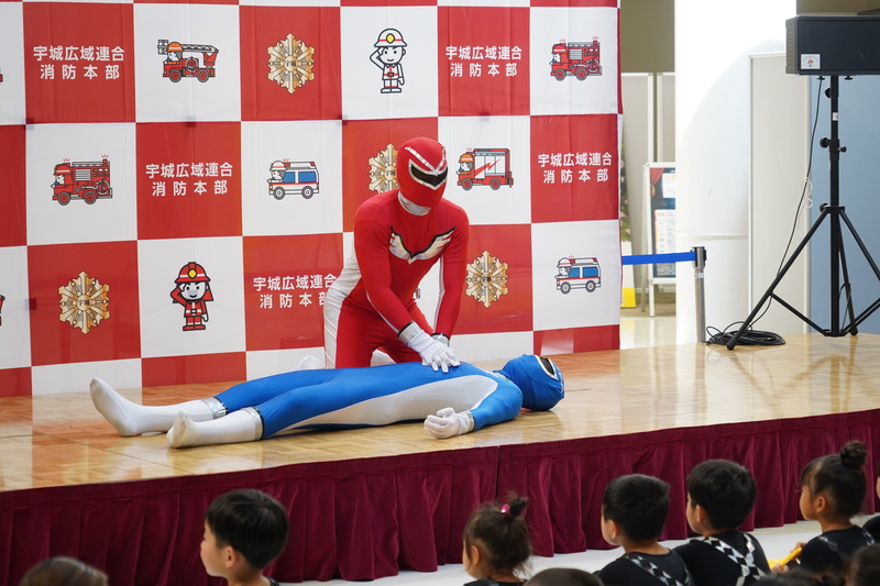 戦隊キャラクターが心臓マッサージを実演する様子