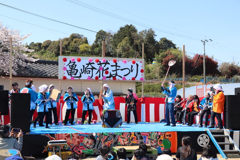 法被を着た参加者たちがステージで亀崎伝統芸能はかり米踊りを披露している写真
