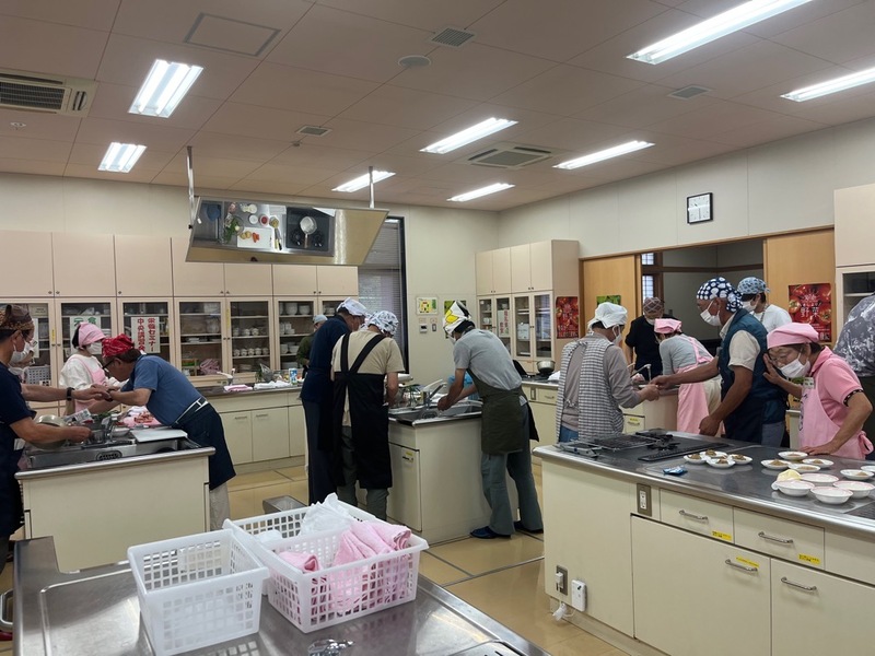 調理場でエプロンとバンダナを身に着けた参加者が、料理をしている写真